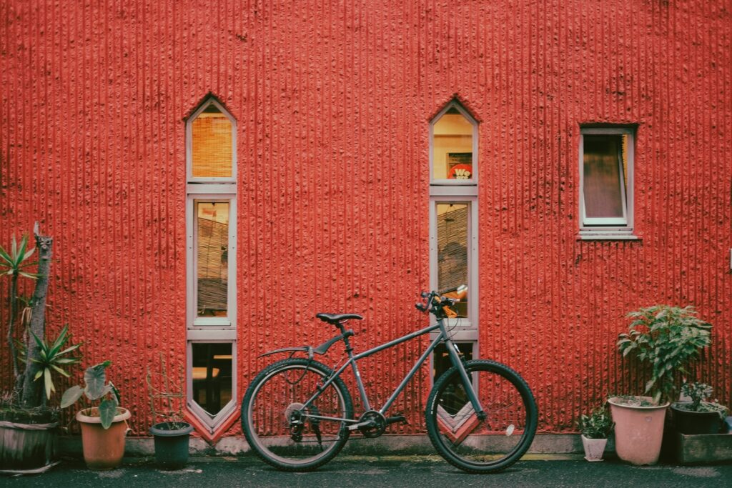 black and white bicycle parked beside red concrete building