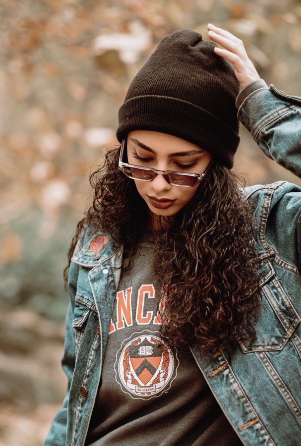 woman wearing blue denim jacket touching her hat while standing and looking down