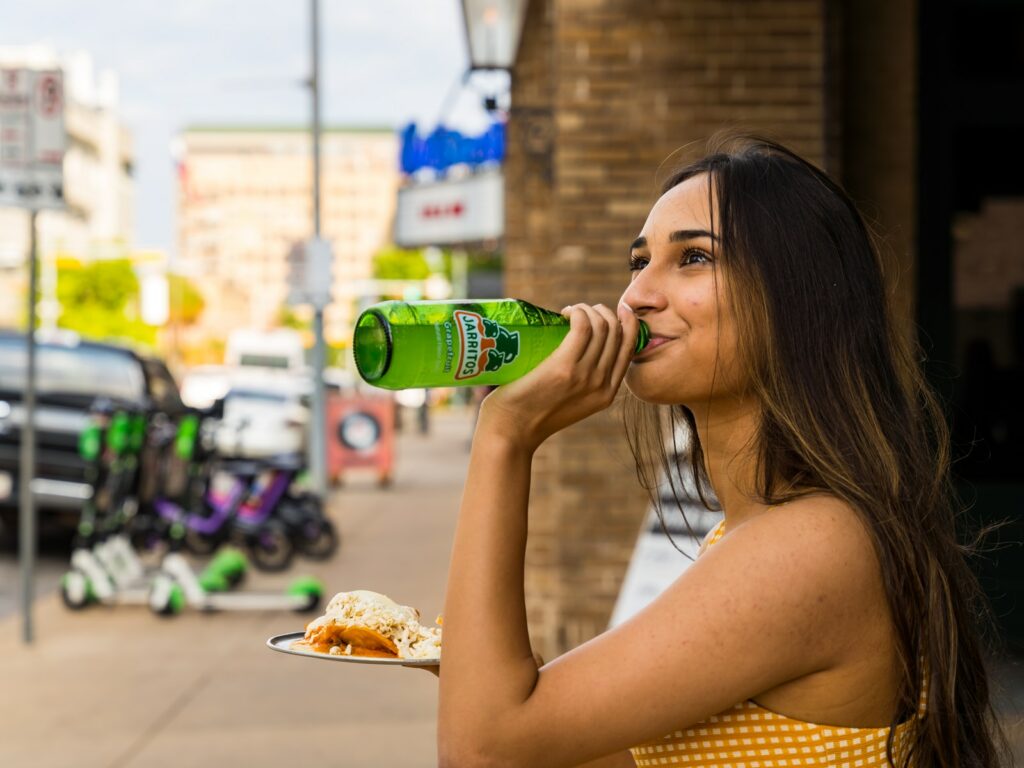 woman in white tank top drinking on green bottle